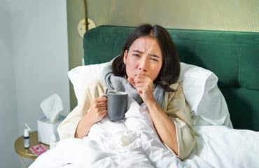 Wanita dewasa batuk di malam hari sambil berbaring di tempat tidur