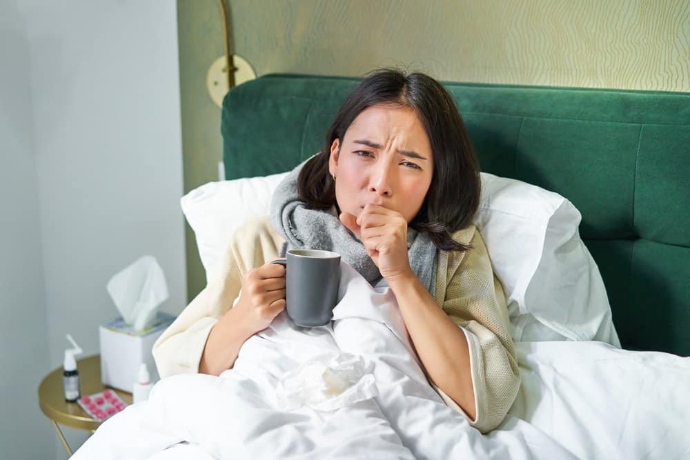 Wanita dewasa batuk di malam hari sambil berbaring di tempat tidur